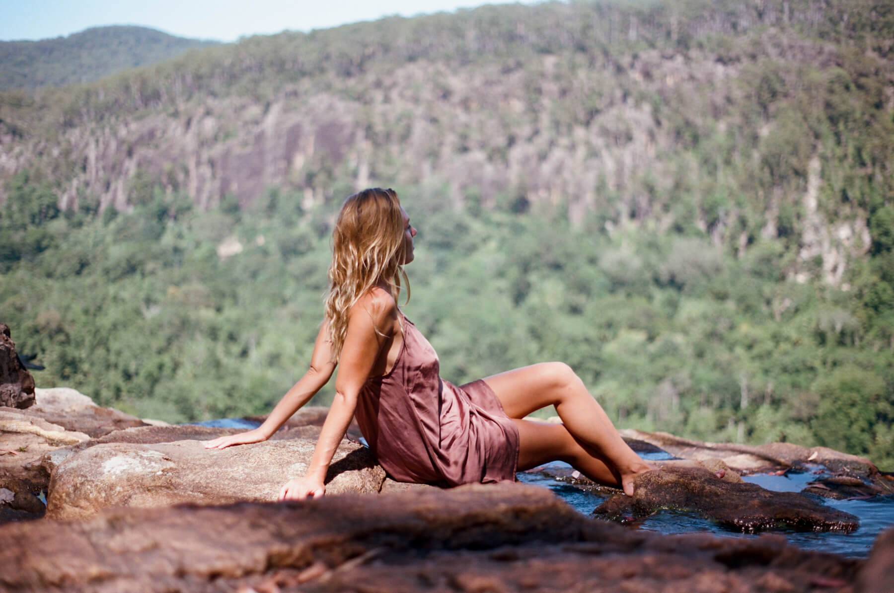 Woman sitting on a rock overlooking a lush green valley