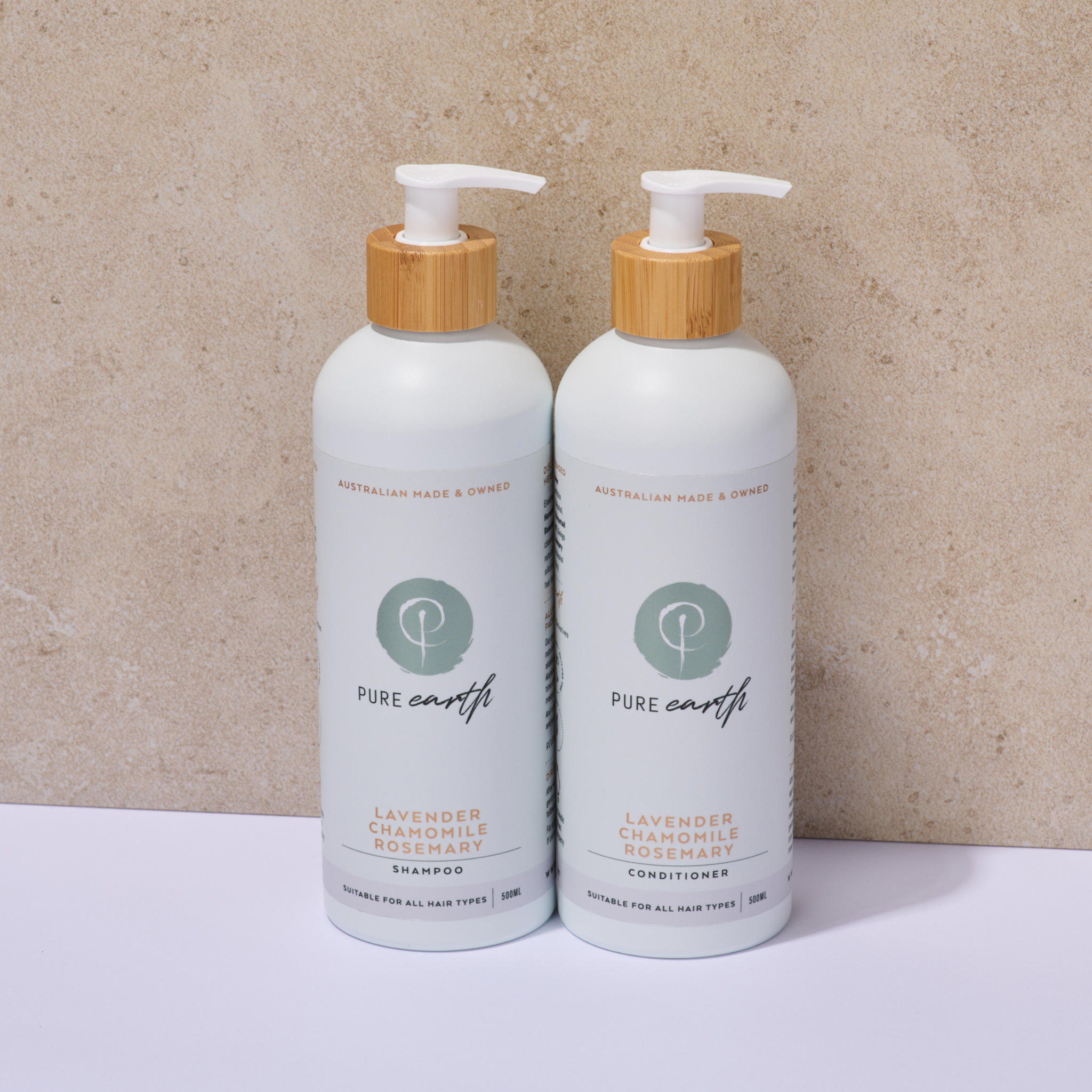 Two bottles of Pure Earth lavender chamomile shampoo and conditioner on a beige background