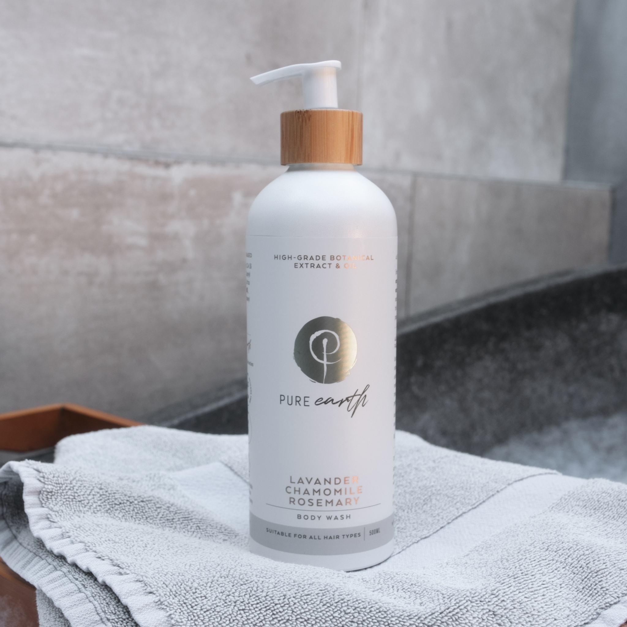 White bottle of Pure Earth body wash with a wooden pump on a towel