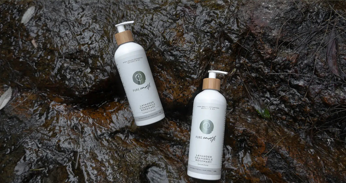 Two bottles of 'pure earth' shampoo and conditioner products on a textured, dark surface.