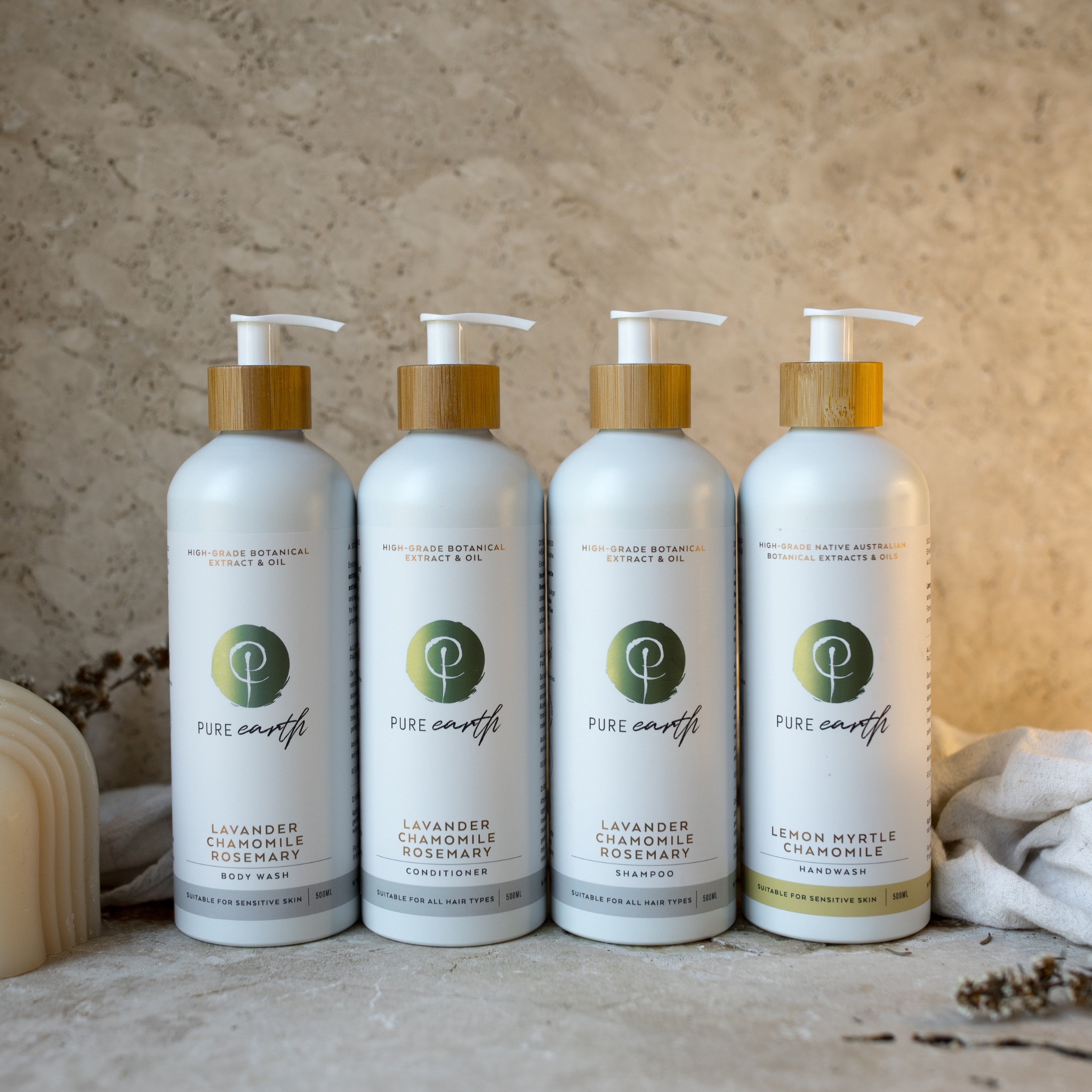 Four bottles of Pure Earth including shampoo conditioner body wash and hand wash on a textured surface with a neutral background