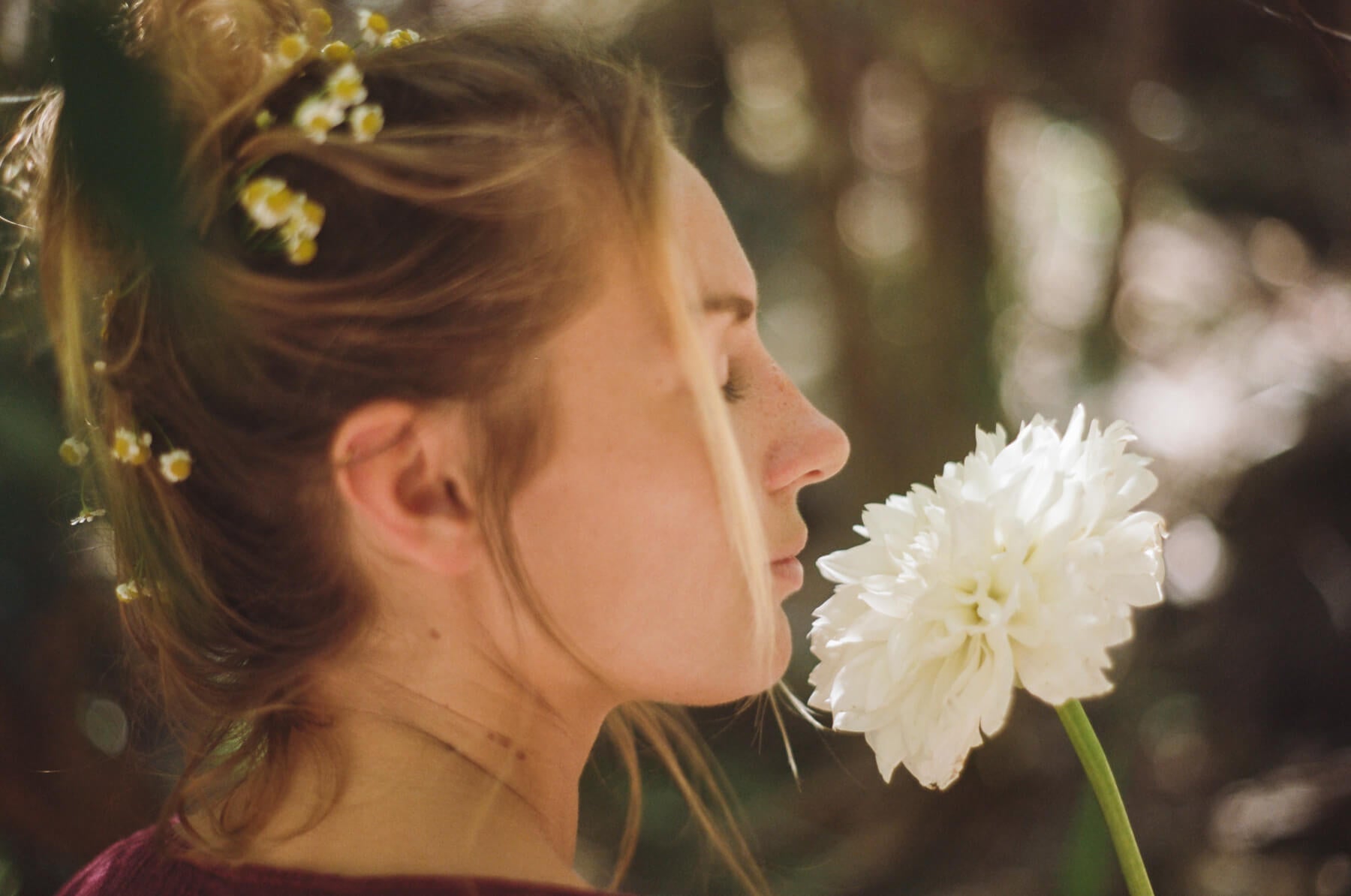 Woman smelling a white flower with a blurred natural background