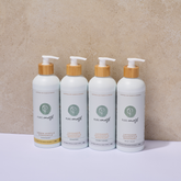 Four bottles of Pure Earth body wash on a beige background and bamboo pumps