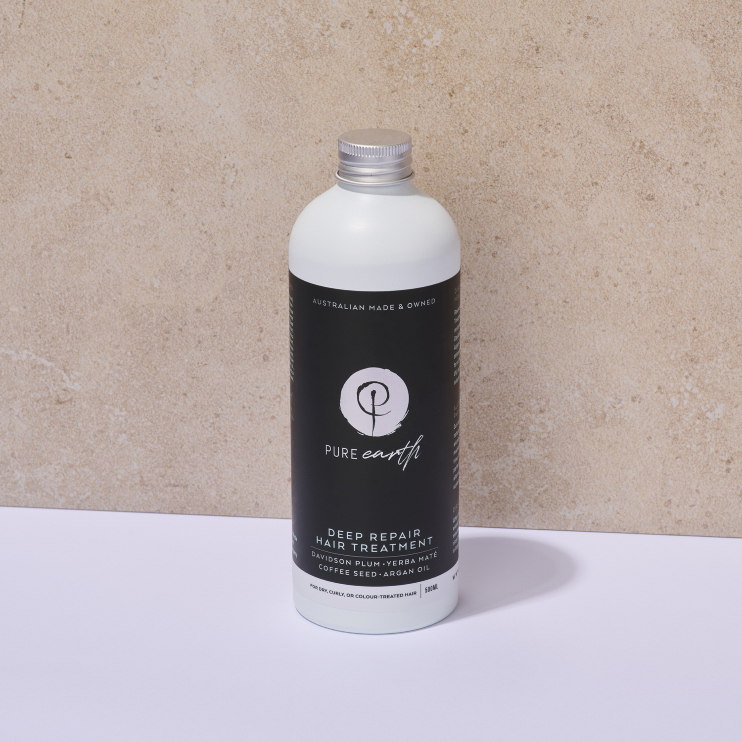 Bottle of Pure Earth deep repair hair treatment mask with aluminium cap on a beige background