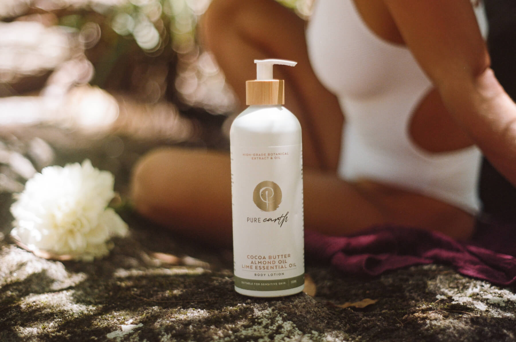 White bottle with bamboo pump and label 'pure earth body lotion cocoa butter almond oil lime esential oil' suitable for sensitive skin and australian made.