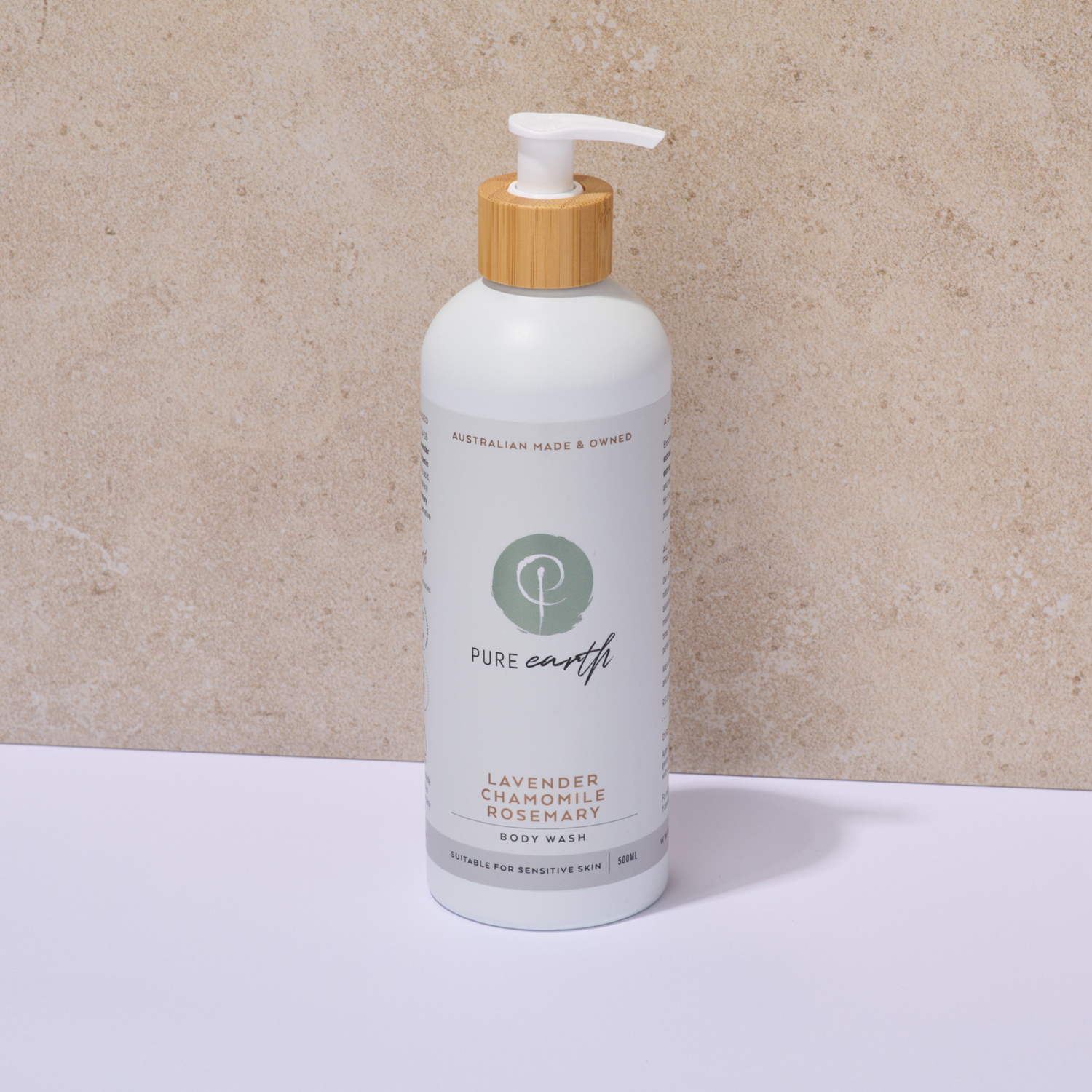 White Pure Earth natural body wash bottle with wooden pump on a beige background