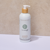White Pure Earth natural body wash bottle with wooden pump on a beige background
