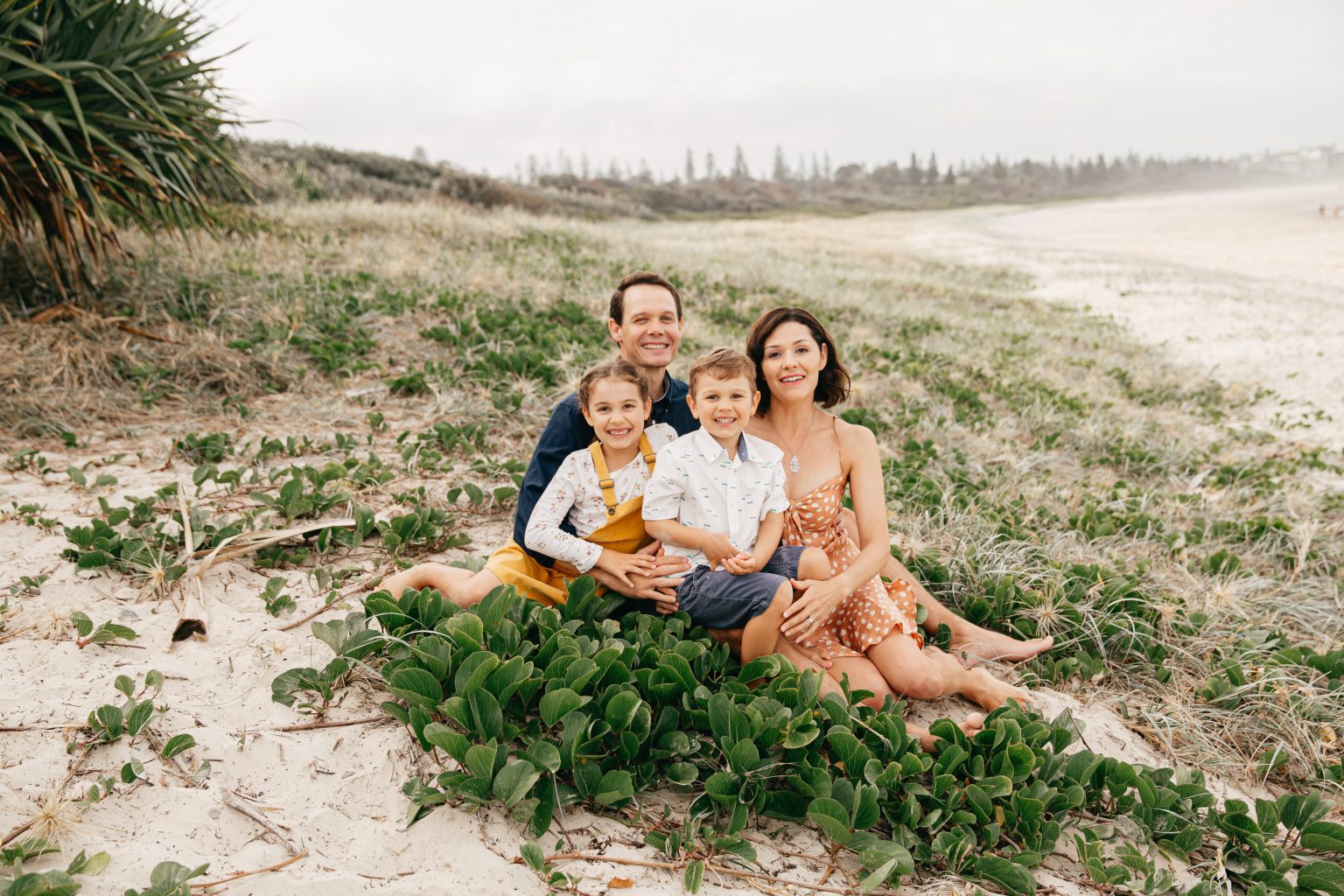 Family picture of father, mother, daughter and son on a natural landscape beach. 