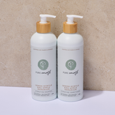 Two bottles of Pure Earth shampoo with pump dispensers on a beige background