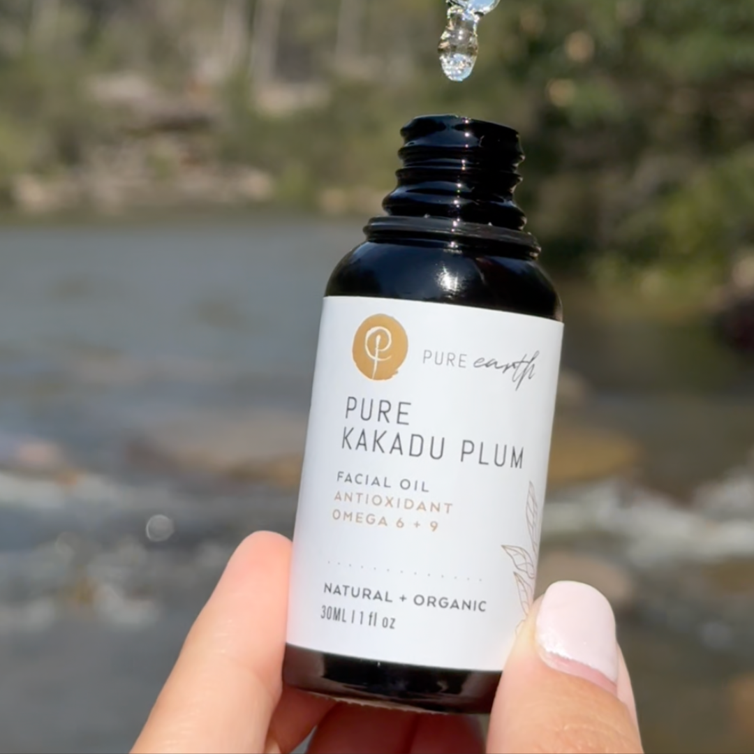 Bottle of Pure Kakadu Plum facial oil held by a hand with a blurred natural background