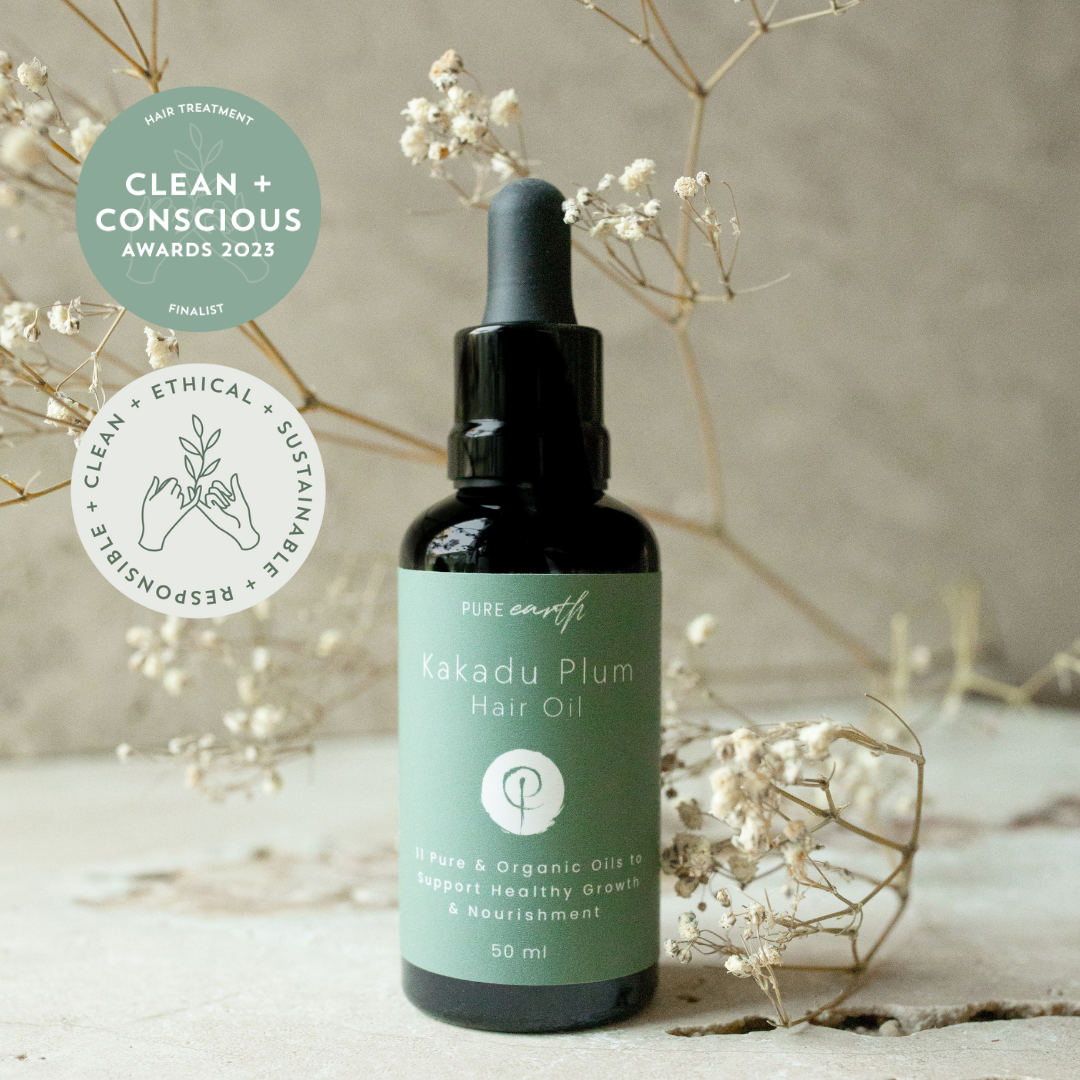 Bottle of Pure Earth Kakadu Plum Scalp and Hair Strengthening Oil Son textured surface and with flowers
