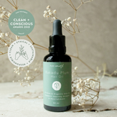 Bottle of Pure Earth Kakadu Plum Scalp and Hair Strengthening Oil Son textured surface and with flowers